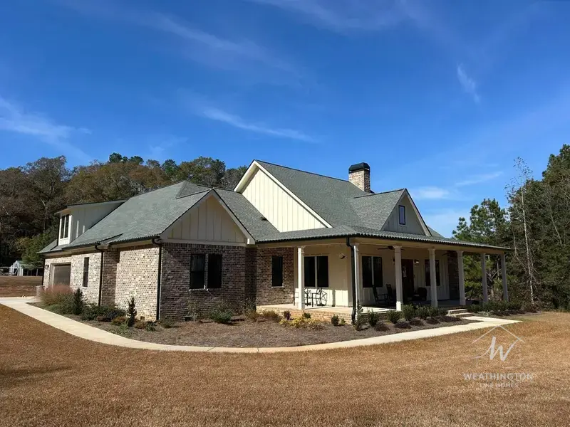 Brick and board-and-batten custom home with chimney and covered porch built by Weathington Fine Homes in Griffin Georgia
